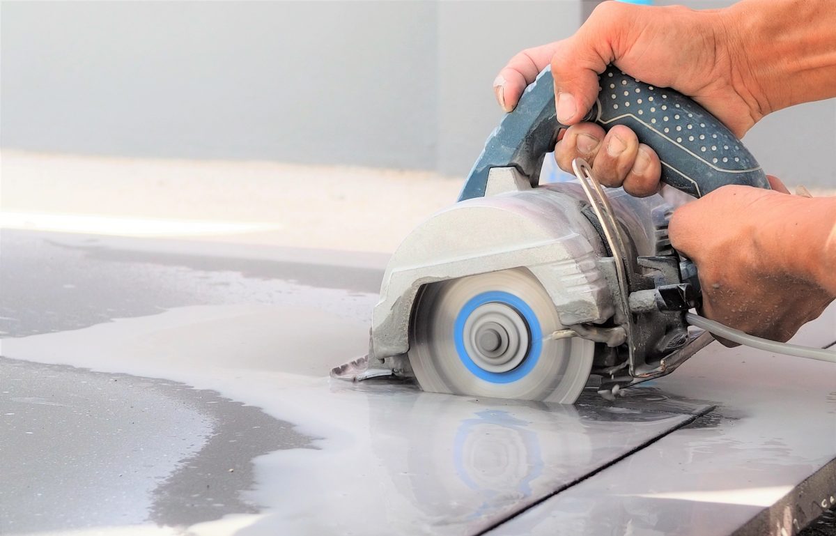 close-up of someone cutting a slab of stone with a hand-held cutting tool.