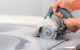 close-up of someone cutting a slab of stone with a hand-held cutting tool.