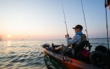 Young man in a kayak on the sea fishing at sunrise in Canada